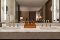 3-slot lacquer amenity holder on hotel bathroom vanity between sinks with three amenity bottles