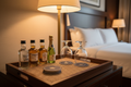 Wood frame pandan insert minibar tray with spirit bottles, glasses, and coaster stack under warm bedside lamp