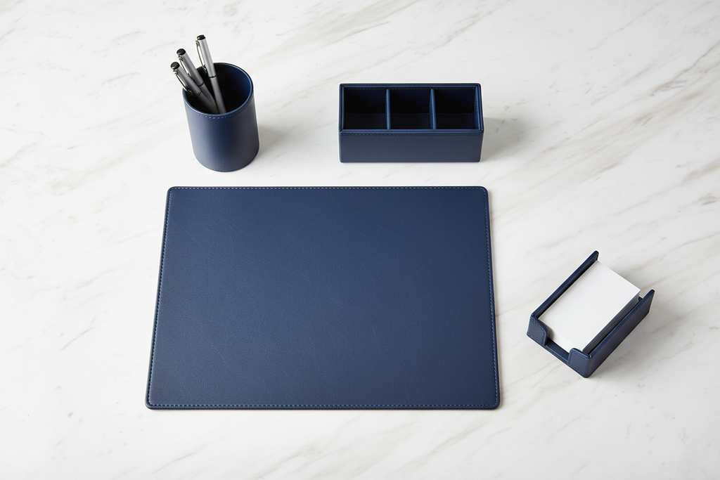 Overhead flat-lay of 4-piece navy leatherette desk set arranged in natural desk layout on white surface