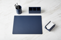 Overhead flat-lay of 4-piece navy leatherette desk set arranged in natural desk layout on white surface