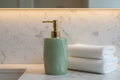 Sage green resin lotion dispenser with brushed brass pump on marble hotel vanity with folded towel